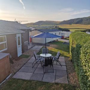 a patio with a table and chairs and an umbrella at Chalet 88 in Aberystwyth