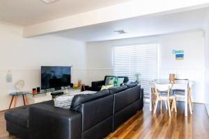 a living room with a black couch and a table at Cockatoo House in Sussex inlet