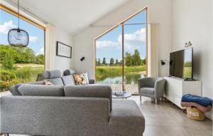 sala de estar con sofás, TV y ventanas grandes. en Awesome Home In Stubbekbing With Kitchen, en Stubbekøbing