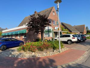 a building with cars parked in a parking lot at Pension Nordlicht in Norddeich
