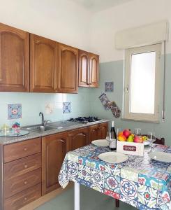 a kitchen with wooden cabinets and a table with fruit on it at Il Giardino Di Capo Vaticano B&B and Apartments in Capo Vaticano