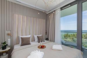 a bedroom with a large bed with a large window at Cristallo Apartament Luxury Resort & SPA - Sea View by Renters Prestige in Międzyzdroje