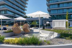 a patio with chairs and umbrellas in front of a building at Cristallo Apartament Luxury Resort & SPA - Sea View by Renters Prestige in Międzyzdroje