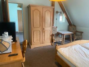 a bedroom with a wooden cabinet and a bed and a desk at Landhotel Waldschänke in Berlin