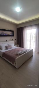 a bedroom with a large bed and a large window at olivegrove in Sidari