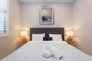 a bedroom with a large white bed with two lamps at Luxury Modern Escapia in Fremantle