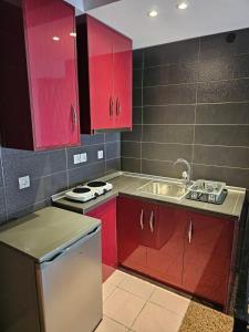 a kitchen with red cabinets and a sink at Adonis Apartments in Paralia Katerinis