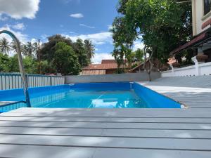 a blue swimming pool with stairs in front of a house at Vongprachan Backpackers Hostel in Luang Prabang