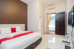 een slaapkamer met een bed en een flatscreen-tv bij RedDoorz Syariah near Taman Air Mancur Bogor in Bogor