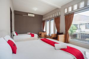 een slaapkamer met 2 bedden en een groot raam bij RedDoorz Syariah near Taman Air Mancur Bogor in Bogor