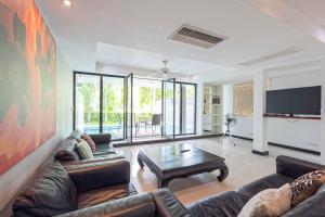 The Fairways Villas - 4 bedroom for 10 guests - 7kms to Patong beach في كاتو: غرفة معيشة مع أريكة وطاولة