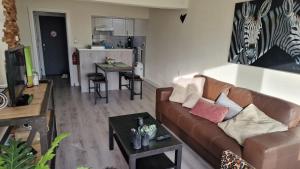 a living room with a brown couch and a kitchen at studio RELAX in Middelkerke