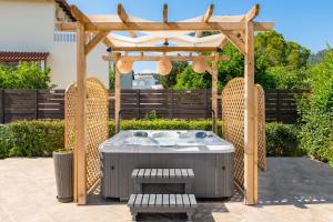 a hot tub under a wooden pergola with two chairs at Villa Montefile in Triánta