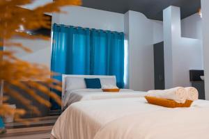 2 Betten in einem Zimmer mit blauen Vorhängen in der Unterkunft GT Seaside Inn in Oslob