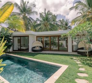 a swimming pool in front of a house with palm trees at Kalea Villas - Private Pool - Free Gym in Kuta Lombok