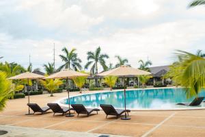 een zwembad in een resort met stoelen en parasols bij River Palm Hotel and Resort powered by Cocotel in Bugallon