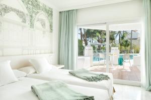 two beds in a bedroom with a view of a patio at Iberostar Selection Marbella Coral Beach in Marbella