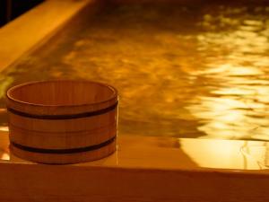 a wooden cup sitting on a table next to a body of water at Ryokan Kohro in Kyoto