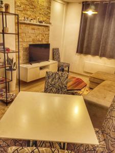 ein Wohnzimmer mit einem Tisch und einem TV in der Unterkunft Milmari Resort N56 Kopaonik free wellnes&spa in Kopaonik