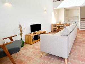 a living room with a white couch and a television at Casa das Piteiras nº3 - Aljezur in Aljezur