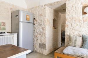 uma cozinha com um frigorífico ao lado de uma parede de pedra em Trullo Solleone con piscine by Wonderful Italy em Carovigno