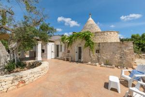 an exterior view of a stone house with a stone wall at Trullo Solleone con piscine by Wonderful Italy in Carovigno