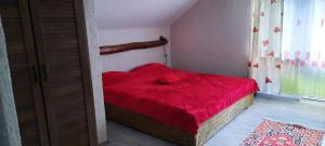 una camera da letto con un letto rosso con una coperta rossa di Casa Licurici a Govăşdia
