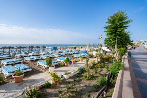 una playa con mesas azules y blancas y el océano en APARTAMENTOS EL CARMEN Carihuela PLAYA, en Torremolinos