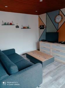 a living room with a couch and a clock on the wall at Calme et détente dans une maison proche de la mer in Neufchâtel-Hardelot