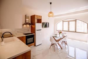 a kitchen with a table and a white refrigerator at Nadia Apartments B in Kalamaki