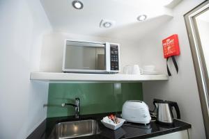 a kitchen with a sink and a microwave on a shelf at Arch Hotel in London