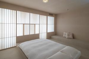 a bedroom with a white bed and large windows at LOG in Onomichi