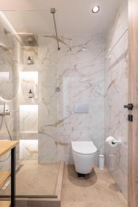 a bathroom with a white toilet and marble walls at Five Senses Of Luxury in Kalandra