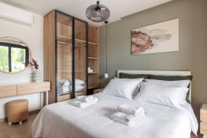 Un dormitorio con una cama blanca con toallas. en Five Senses Of Luxury en Kalandra