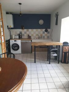 een keuken met een tafel en een wasmachine bij Appartement 6 pers sur l'Aubrac 