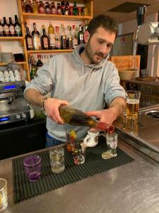 Um homem parado num bar a servir uma garrafa de álcool. em Auberge du Col du Festre em Le Dévoluy