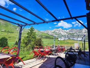 un gruppo di tavoli e sedie su un patio con montagne di Auberge du Col du Festre a Le Dévoluy