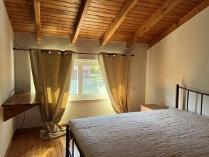 a bedroom with a bed and a window with curtains at Harmony House Corfu in Kynopiástai