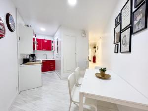 Una cocina blanca con armarios rojos y una mesa y sillas blancas. en Suite Miro Eixample Barcelona, en Barcelona