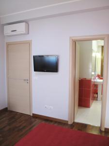 Habitación con puerta y TV en la pared en B&B Santa Caterina en Reggio Calabria
