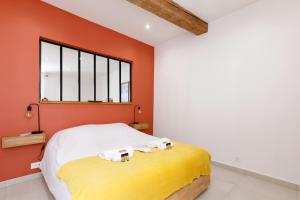 sypialnia z pomarańczowymi ścianami i łóżkiem z ręcznikami w obiekcie Le Cocon Saint Tropez YourHostHelper w Saint-Tropez