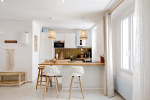a kitchen with white cabinets and white stools at Le Cocon Saint Tropez YourHostHelper in Saint-Tropez
