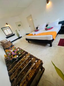 ein Schlafzimmer mit einem Bett und einer Bank mit Blumen darauf in der Unterkunft LOUIS LAKE VILLA in Kandy