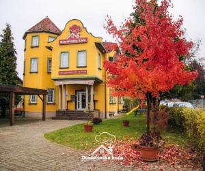 a yellow building with a tree in front of it at Domaćinska Kuća Banja Luka in Banja Luka