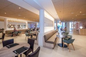 a restaurant with tables and chairs and people sitting at tables at HG Jardín de Menorca in Son Bou
