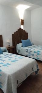een slaapkamer met 2 bedden met blauwe en witte lakens bij Casa Cueva El Almendro in Pegalajar