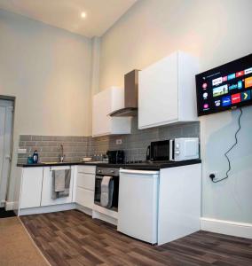 a kitchen with white cabinets and a microwave at Cosy Convenient 1 BR Flat at Central Stoke Near Hospitals and Univesities in Stoke on Trent