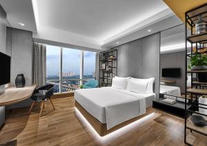 a bedroom with a white bed and a desk with a desk at Nuanza Hotel & Convention Cikarang in Cikarang