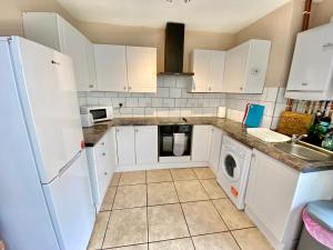 a kitchen with white cabinets and a washer and dryer at EasyRest House 1 Grantham - 6 Beds & Free Parking - Spacious & Comfy - Access to A1, Town Centre & Shops in Grantham