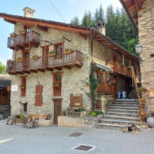 a stone building with wooden balconies and stairs at Albergo diffuso La Marmu Osteria della Croce Bianca in Marmora